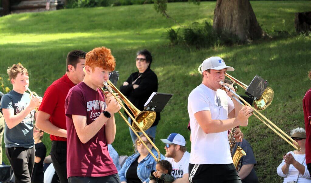 Two male high school students march and play trombone in the Tivoli Fest parade.