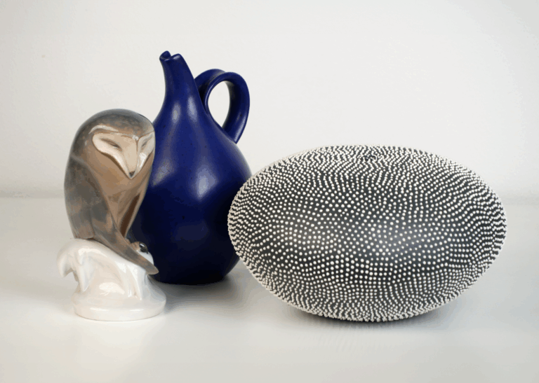 A ceramic owl, blue vase, and textured black and white ceramic piece