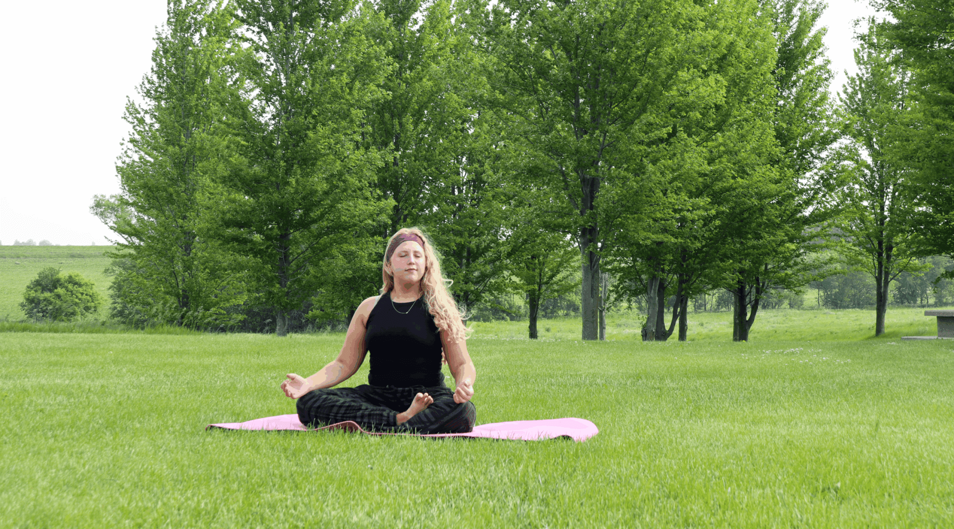 A woman practicing yoga on a pink yoga mat on the Jens Jensen Prairie Landscape Park.