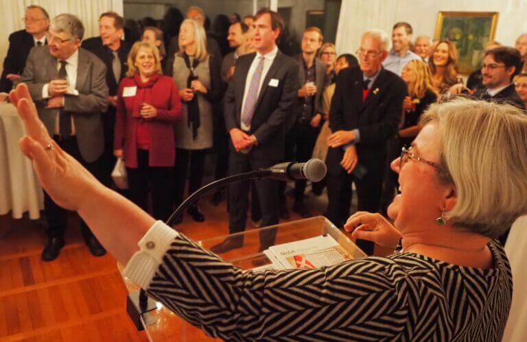 Tova Brandt gestures with her left arm while presenting at an event.
