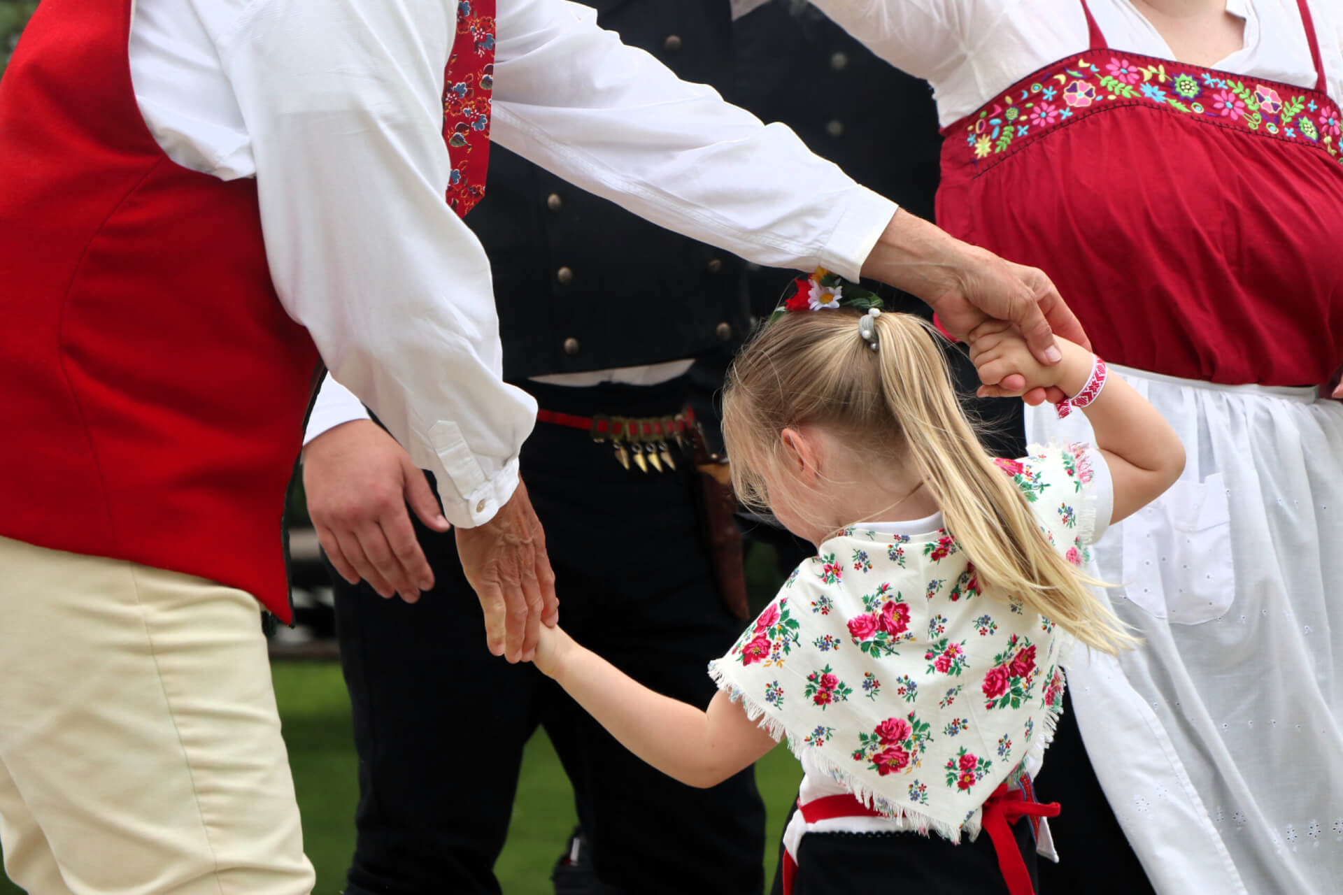 A young girl dressed in a Danish folk costume is spun by an older gentleman also dressed in a Danish folk costume.