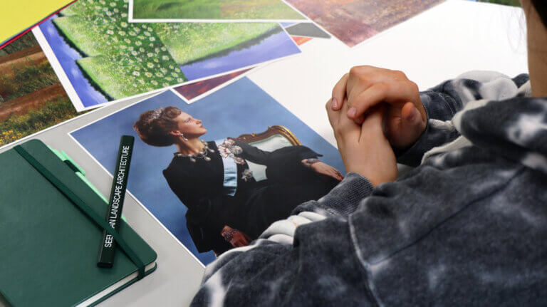 A student clasps their hands before a photo of Queen Margrethe.