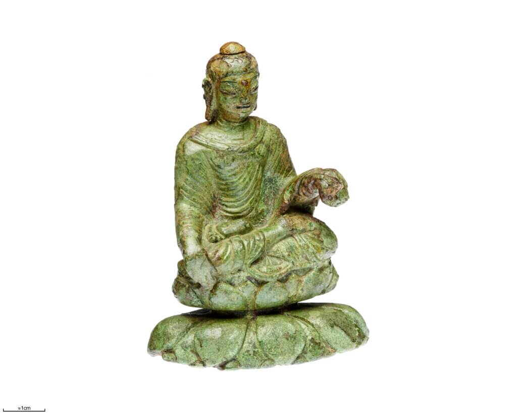 a small green statue of a man sitting cross-legged