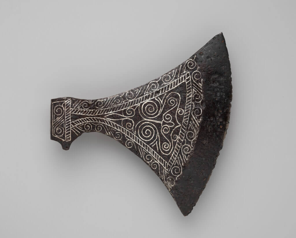 an axe head with elaborate silver designs.