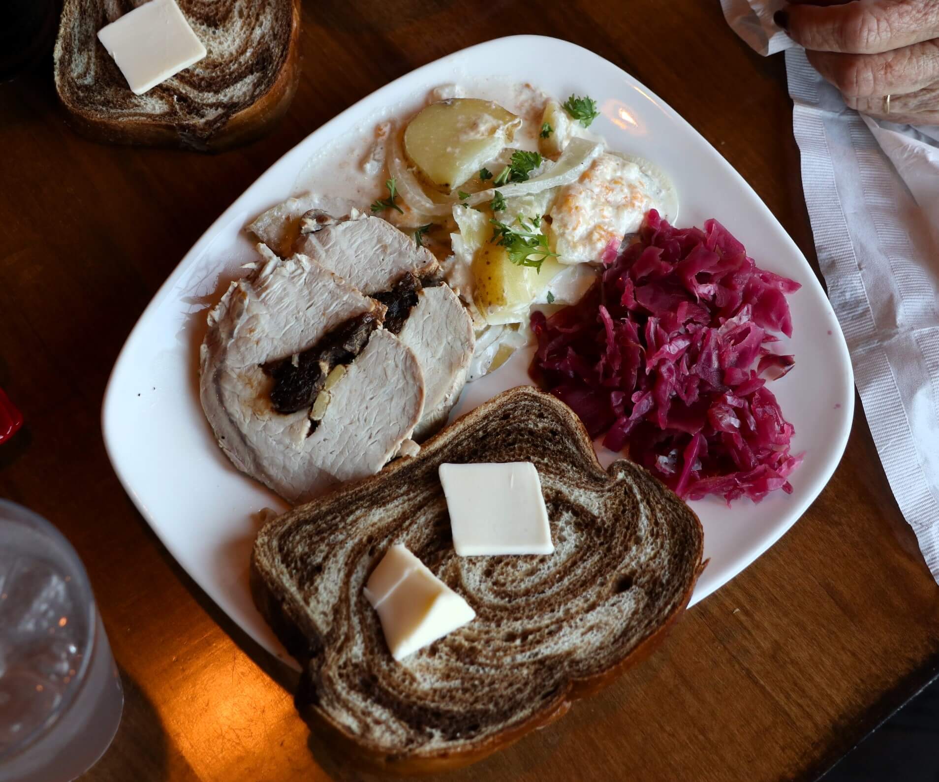 A plate with pork loin, rye brad, rodkal, and potatoes.