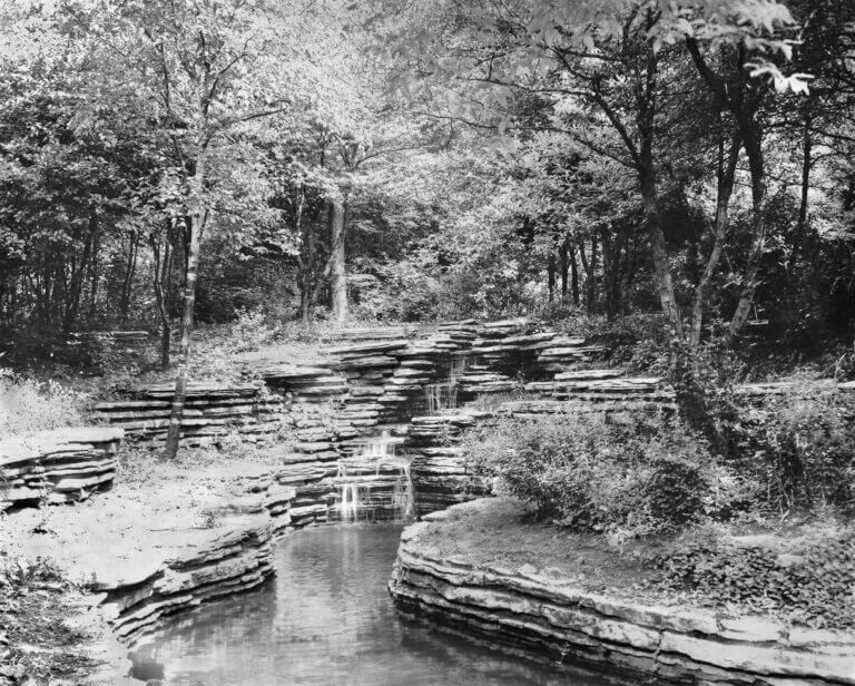 black and white photograph of a small pond and waterfall.