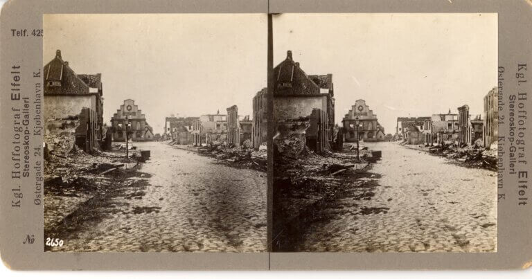 An old photograph of a cobbled street with destroyed buildings