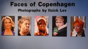 A wall with five photographs of different people.