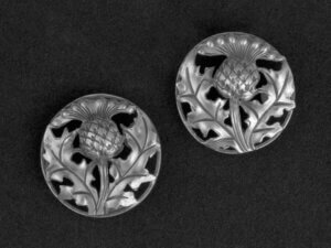 Two silver overcoat buttons with a thistle as motive.