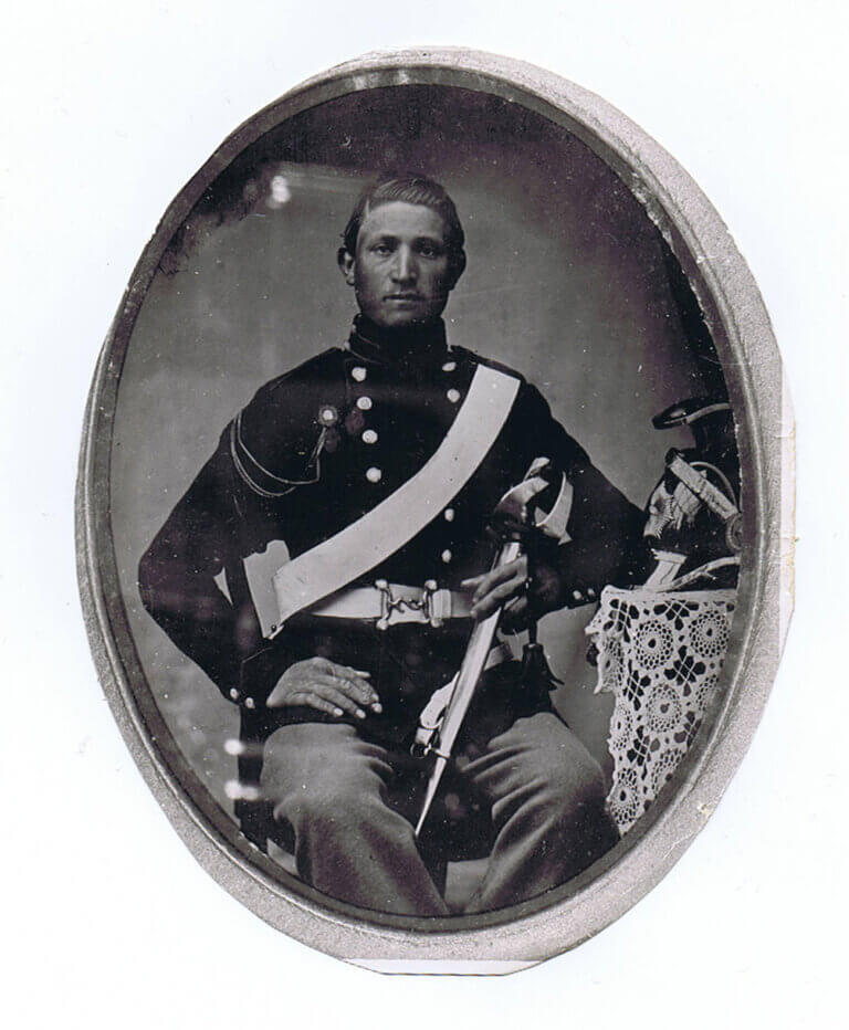 A photograph of a soldier sitting, he is in an old uniform in dark color.