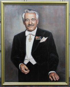 Portrait of a man with gray hair wearing a tuxedo with medals.
