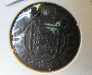 Close-up of an old copper coin. In the middle is the Danish coat of arms.