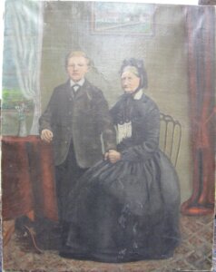 Oil painting of a boy standing beside a sitting elderly woman. They are both wearing dark clothing.