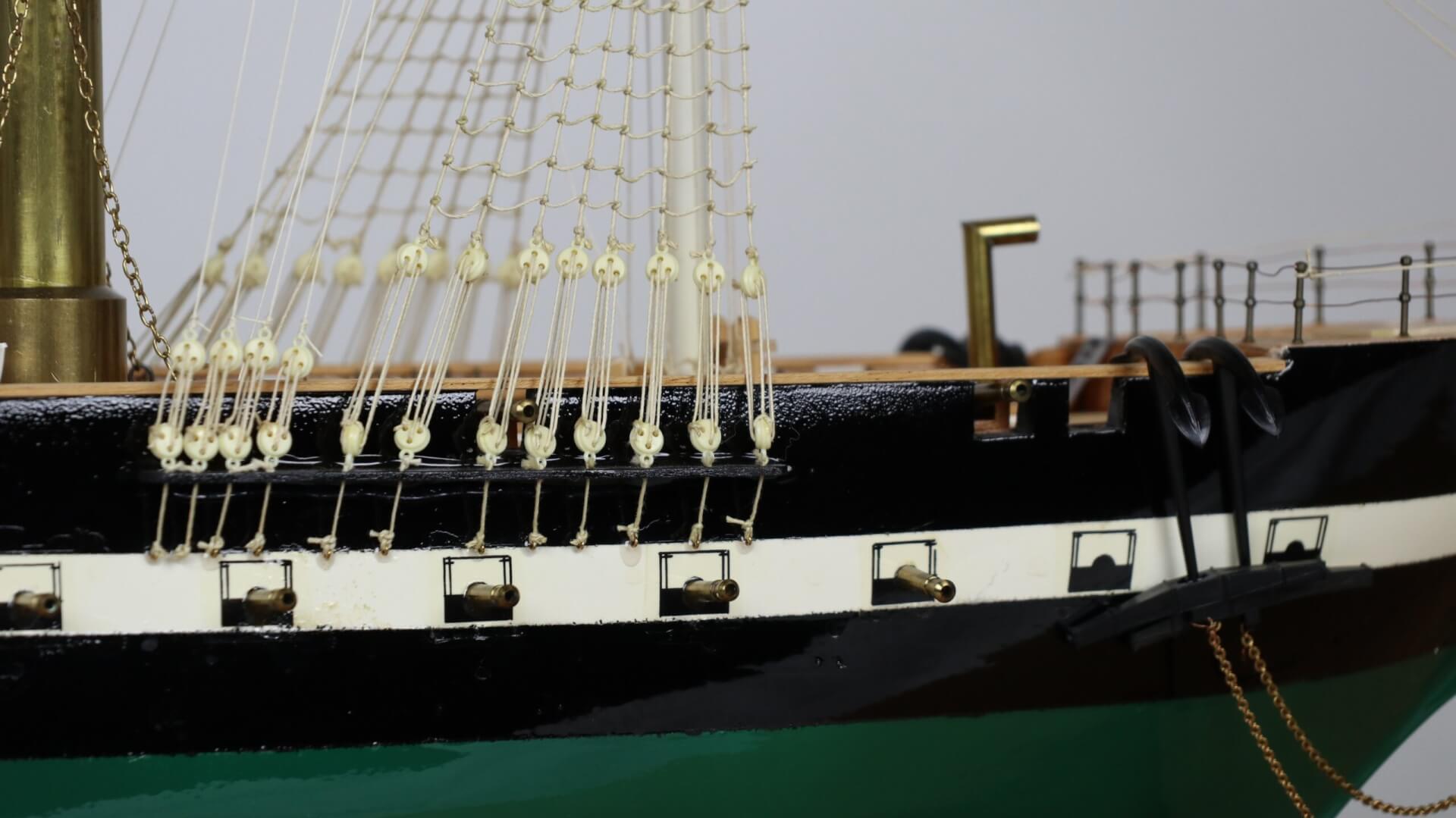 Close up of cannons on the side of a model ship. Anchors are on the right.