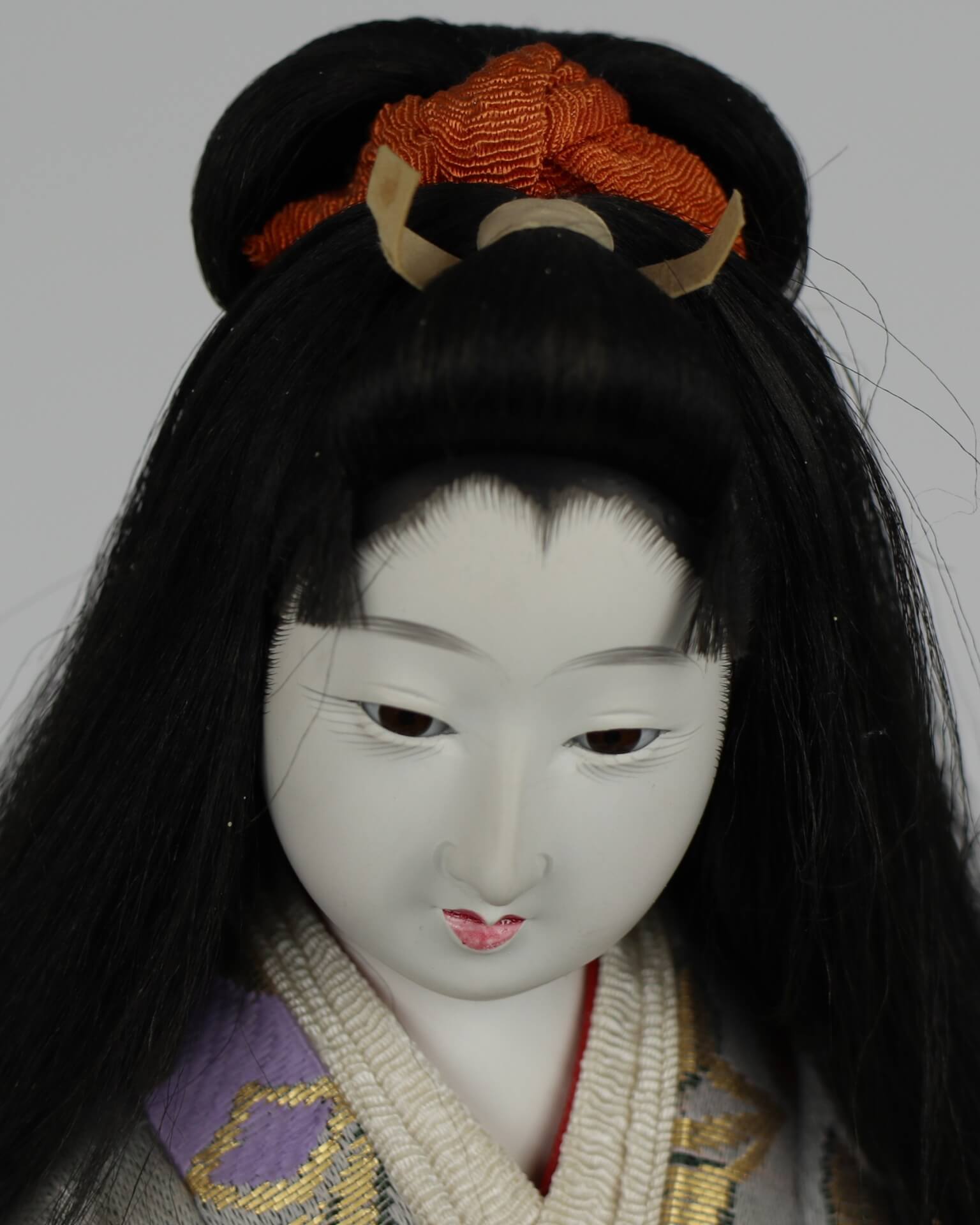 Close up of doll's hair style. The hair is styled in a bun that lets hair encircle her face.