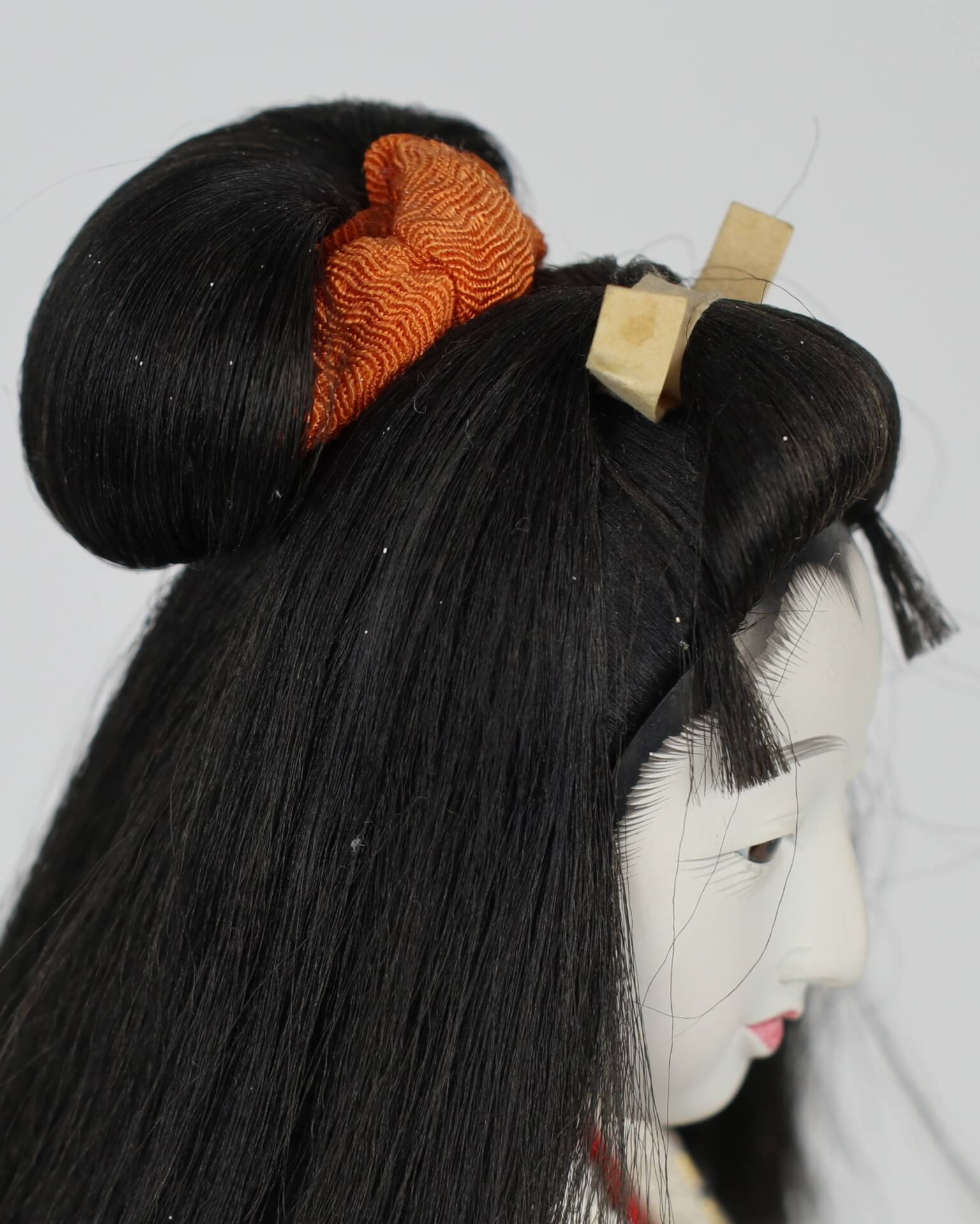 Close up of doll's hair style. The hair is styled in a bun that lets hair encircle her face.