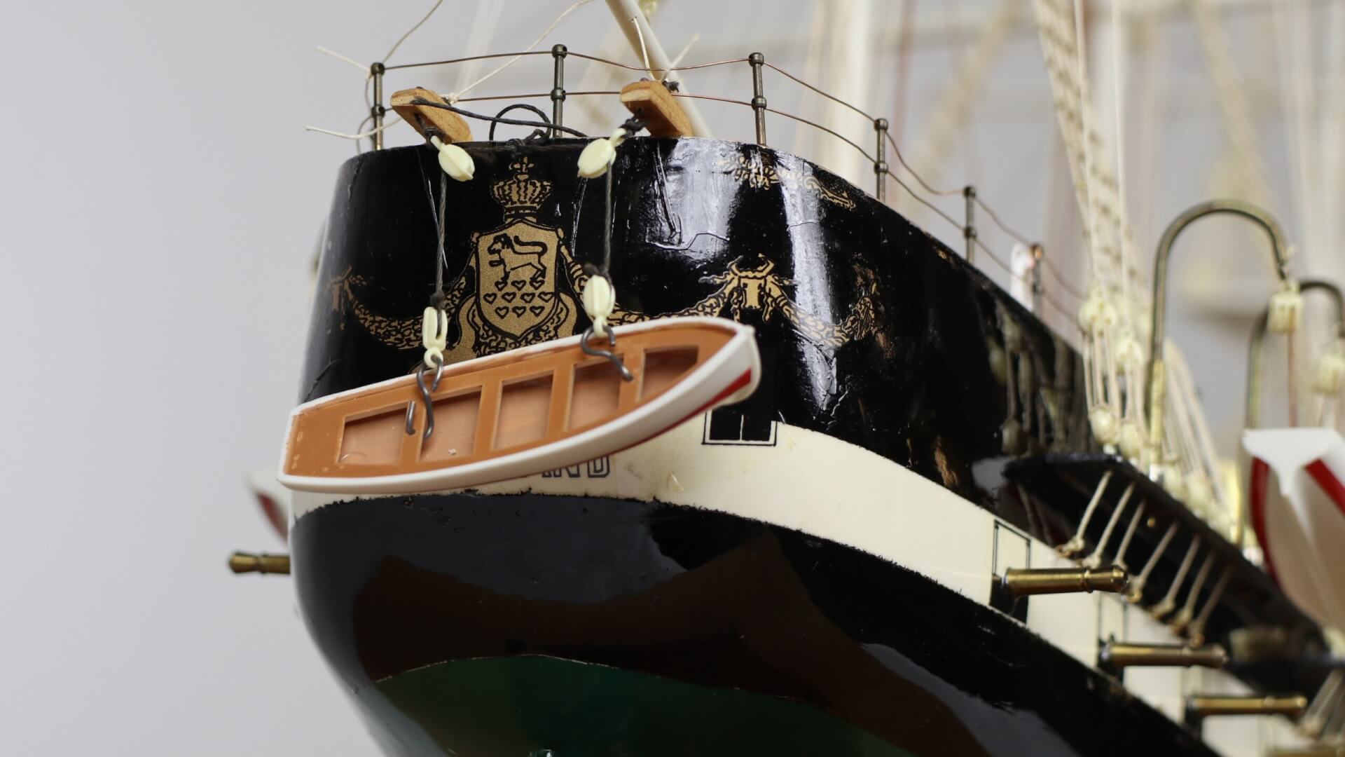 Close-up of model ship's stern, featuring a crest emblem.