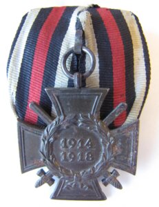 Metal cross with a laurel wreath, over a black, white, and red striped ribbon.