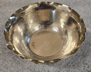 Silver bowl with divots around the outer rim.