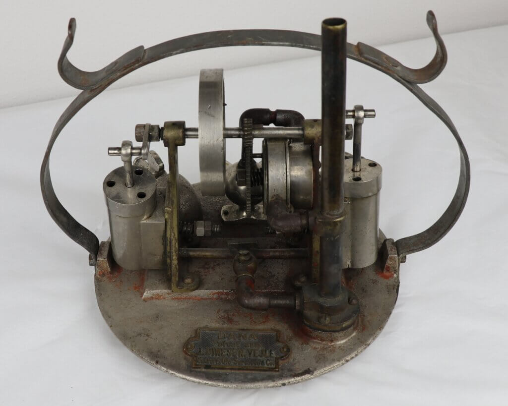 Metal machine model with gears and pipes on a circular base.