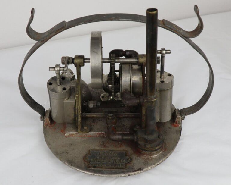 Metal machine model with gears and pipes on a circular base.