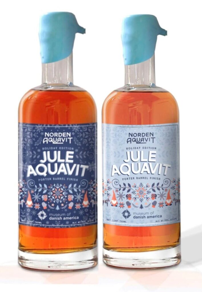 Two bottles of aquavit. The one on the left has a darker blue label, while the one on the right has a lighter blue label. Titled "Jule Aquavit,' the label features elements of Scandinavia.