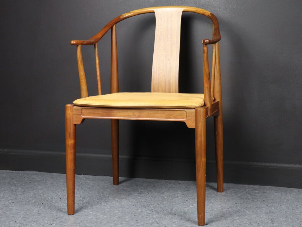A wooden chair with a curved backrest. It has a beige seat cushion.