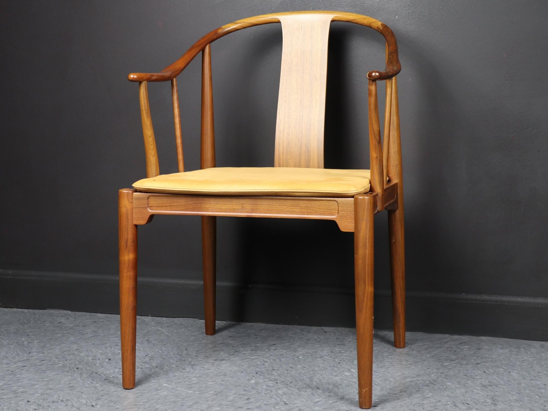 A wooden chair with a curved backrest. It has a beige seat cushion.