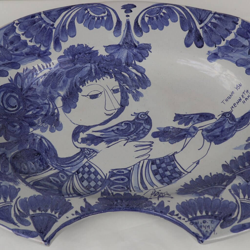 Large platter, painted in blue and white. The image depicts a human figure holding two birds. Above the rightmost bird is text reading "Thank You Kenneth Hansen."