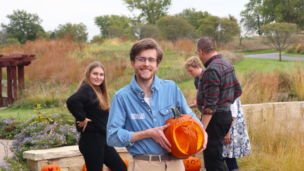A staff member poses with a pumpkin he carved.