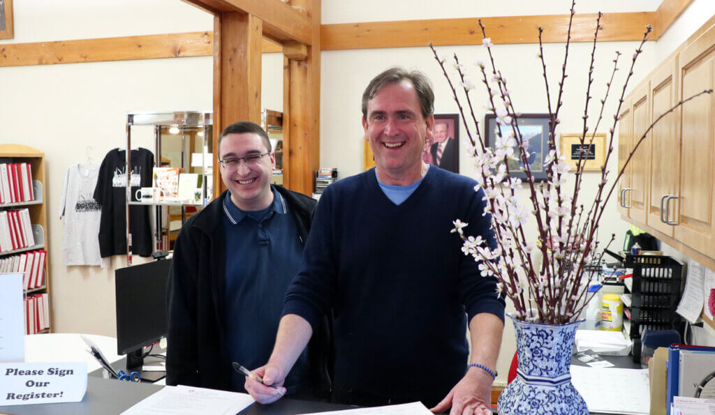 Two staff members stand behind the welcome desk at the Museum's Genealogy & Education Center.